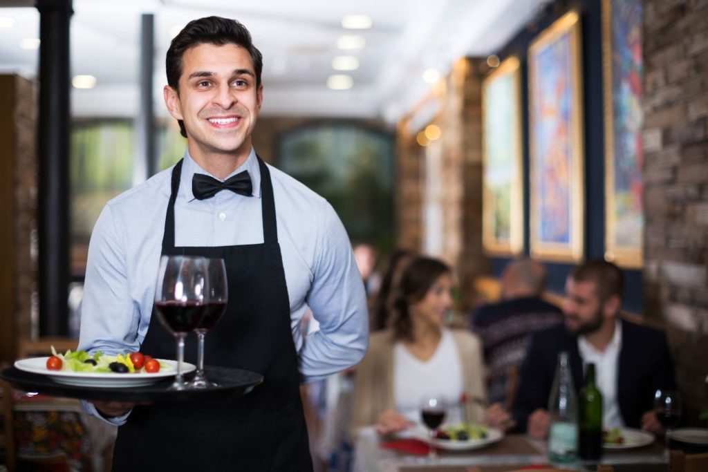 Camarero sriviendo en un restaurante para mantener la seguridad e higiene